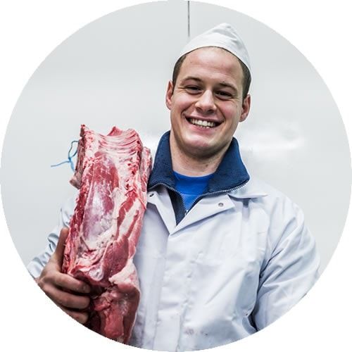 Een lachende slager met een stuk varkensrug in de hand